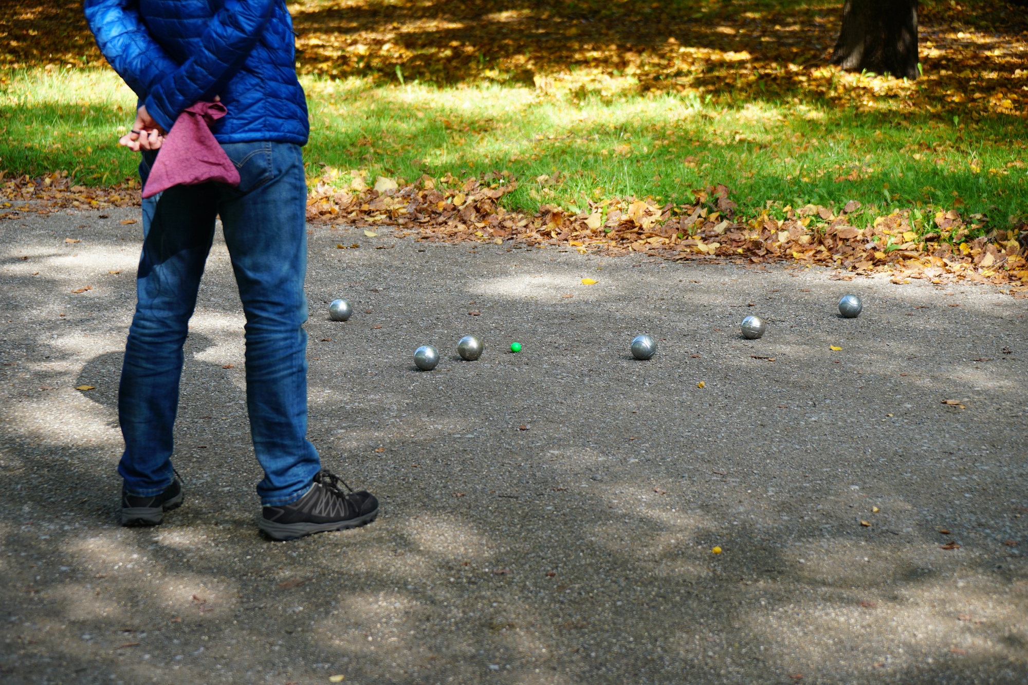 unrecognizable person playing boule or petanque game outdoors